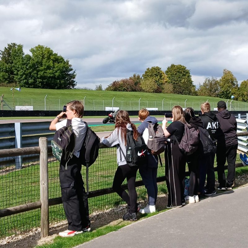 Students Watch motorcycles drive past them at high speeds