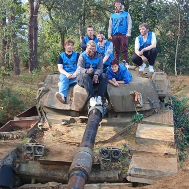 Students pose for a photo on top of a tank.