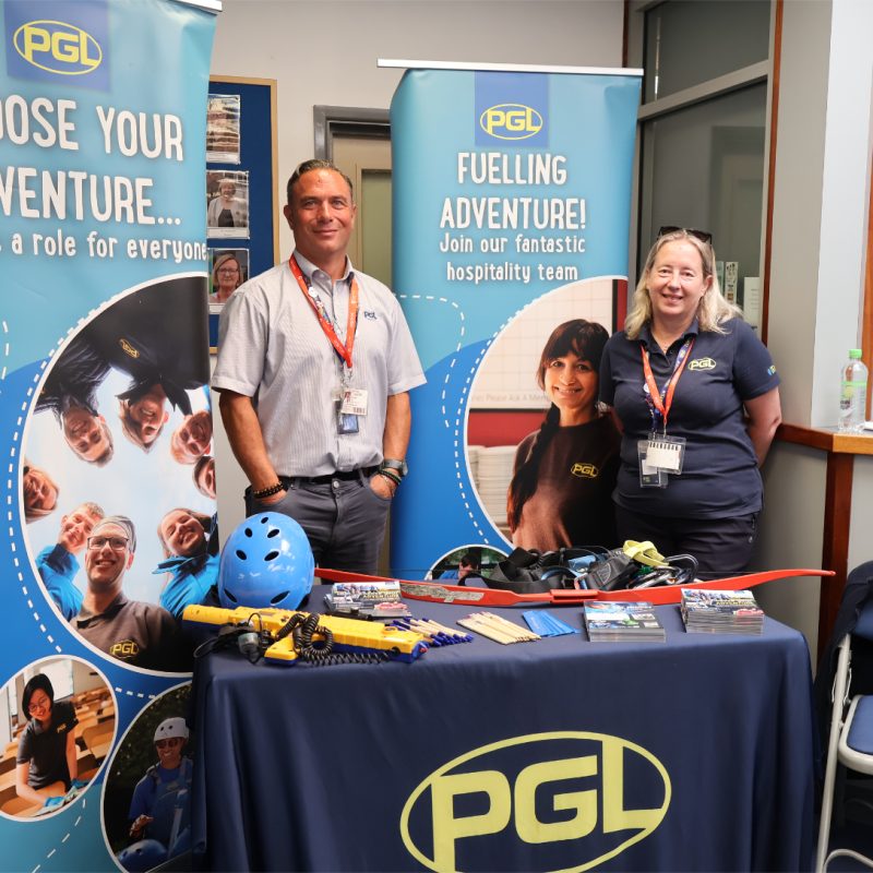 A man and a woman stand behind a PGL Stand.