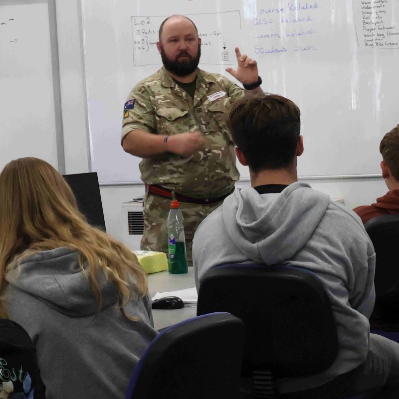 a man in a military uniform addresses students
