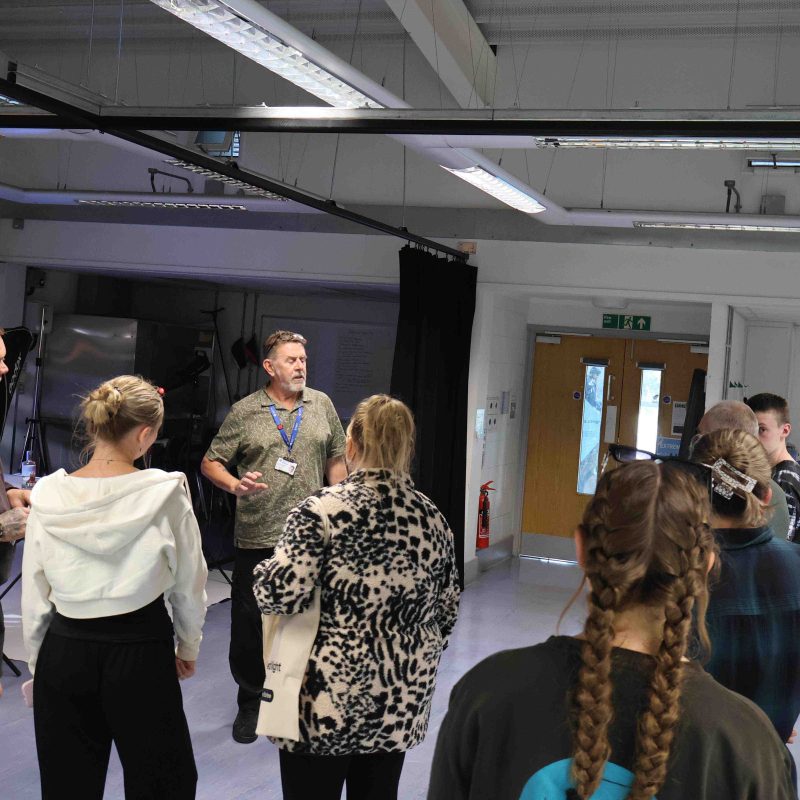 a lecturer speaks to a crowd in a photography studio