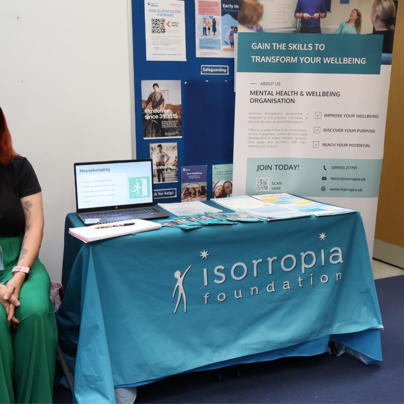 A Woman sits beside the Isorropia Stand
