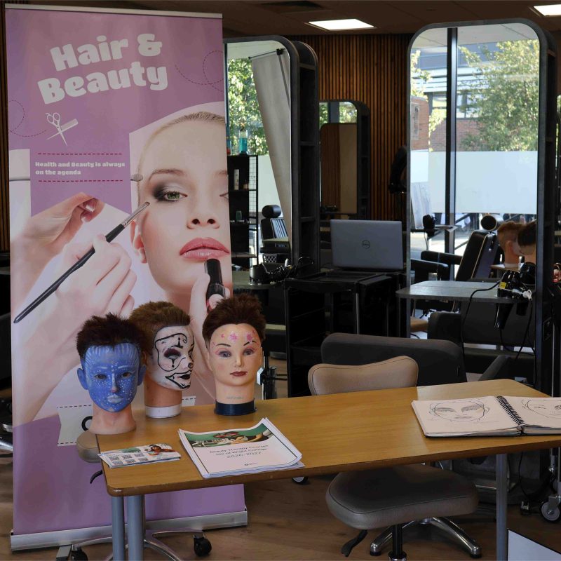 a hairdressing table is set up with a pop up banner and a dummy head with hair