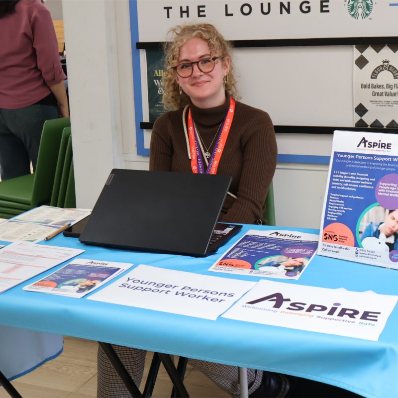 A woman sits behind the Aspire stall.