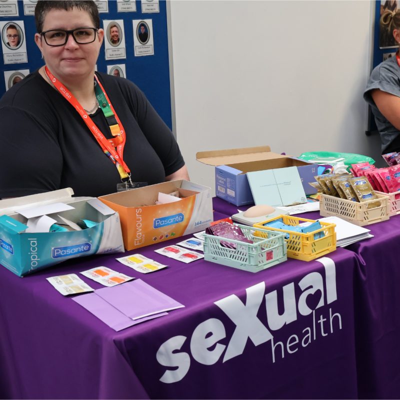 A woman sits behind the sexual health nurse stand.