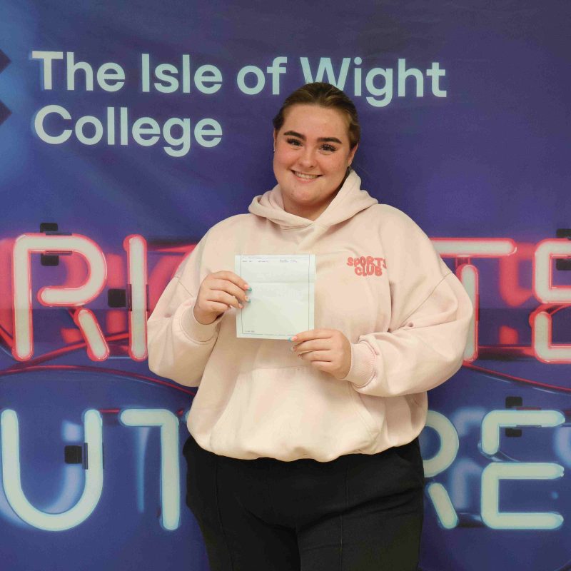 A female student poses for a photo with her GCSE results