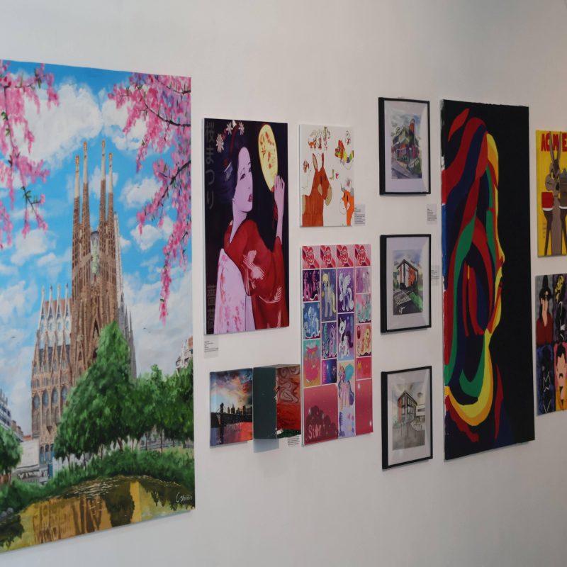 Paintings and drawing are displayed on a wall.