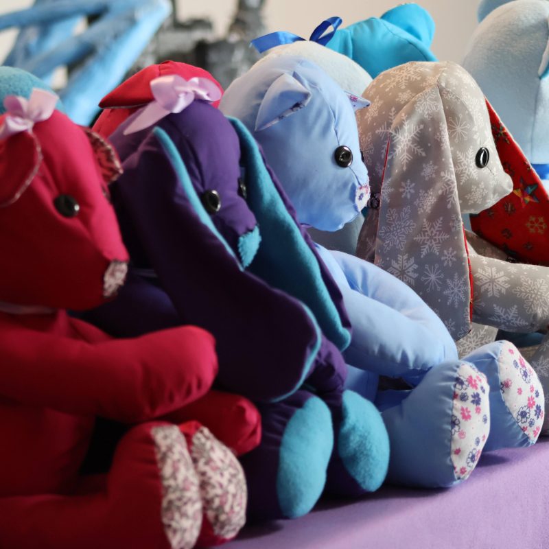 Handmade teddy bears sit on a table top.