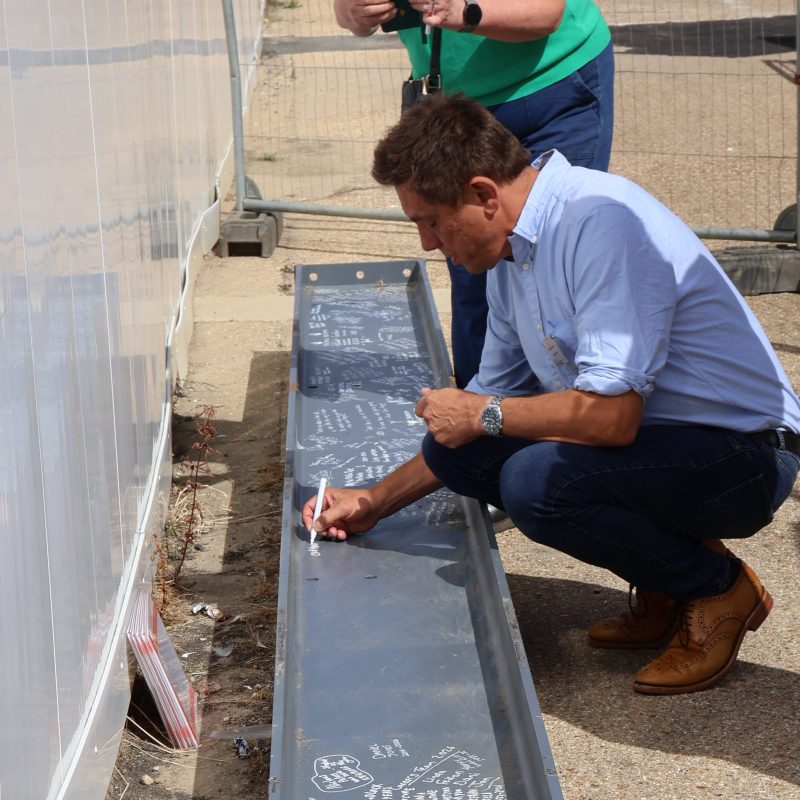 A man signs the steel beam.