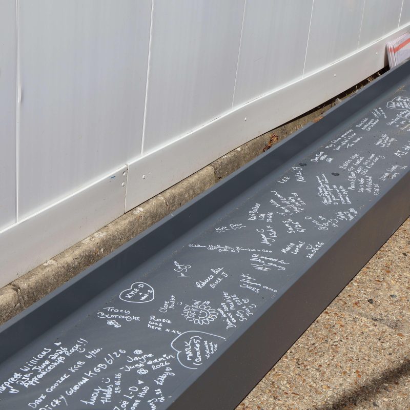 A picture of the beam on the ground filled with various different signatures and messages.