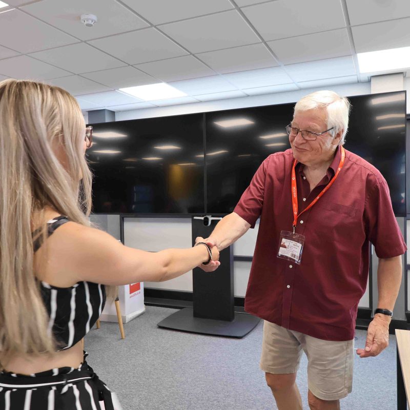 A Student shakes the hand of a Councillor handing out certificates.