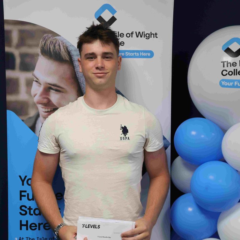 A Male student poses in front of balloons with his results