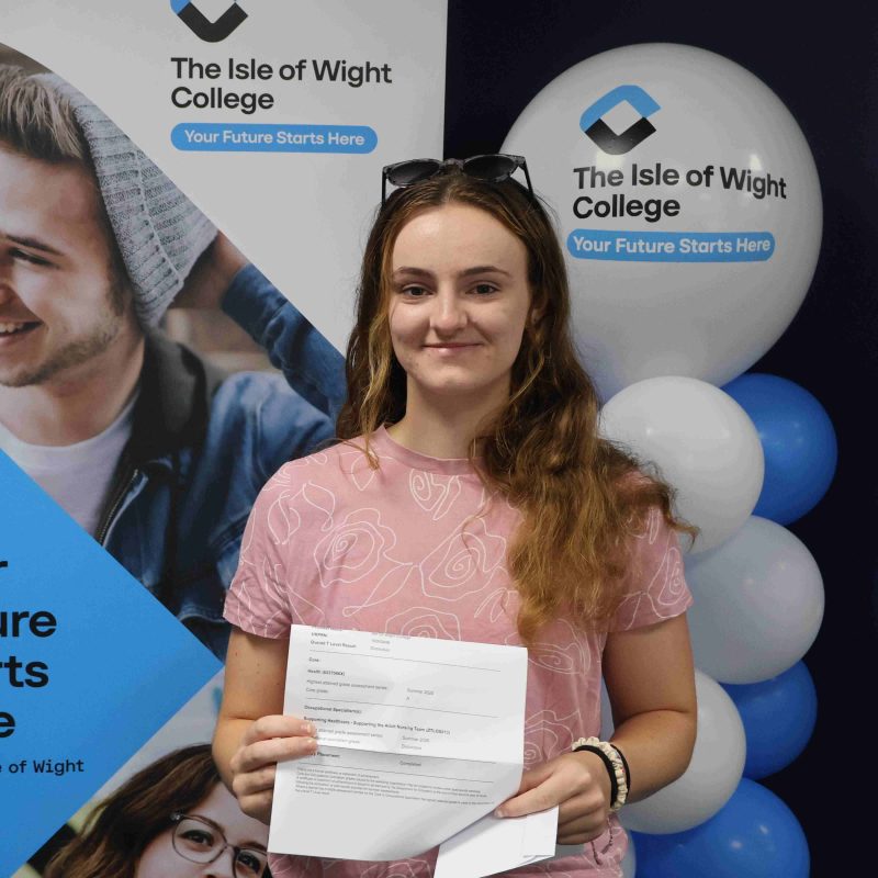 a female student poses in front of balloons with her results