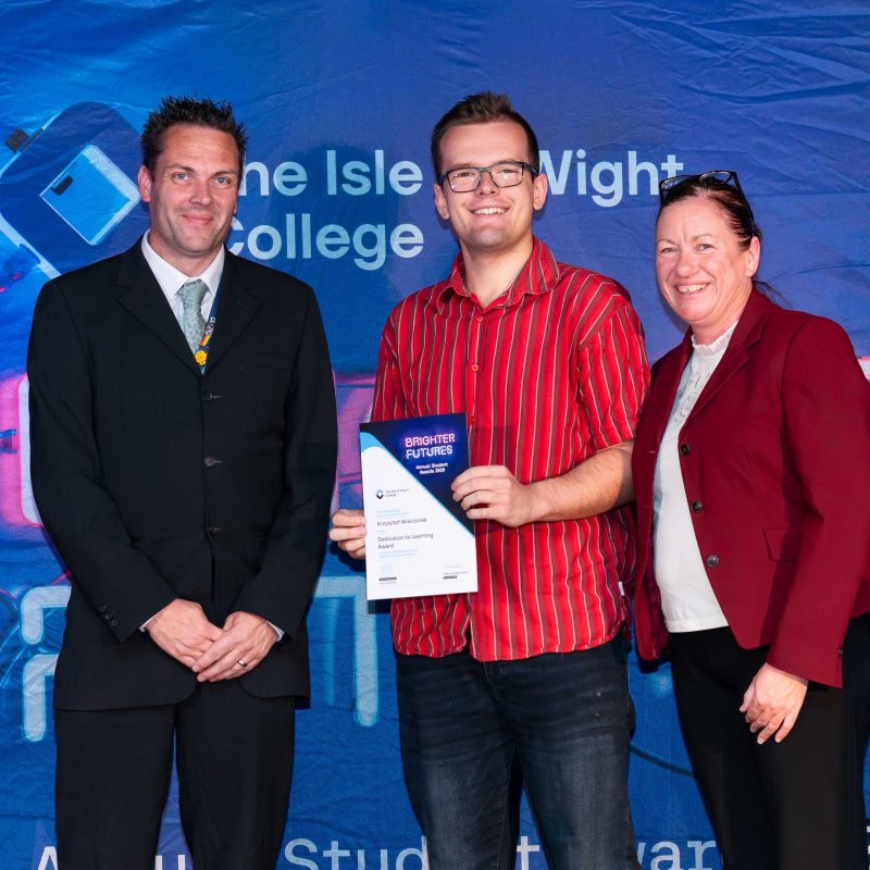 a student receives his certificate and poses with his lecturer and principal