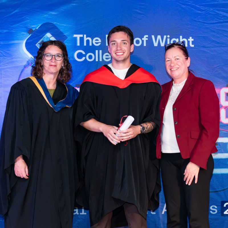 A Higher education student receives his awards and poses with his lecturer and principal
