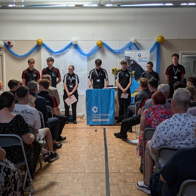 Students address a crowd at the front of a hall