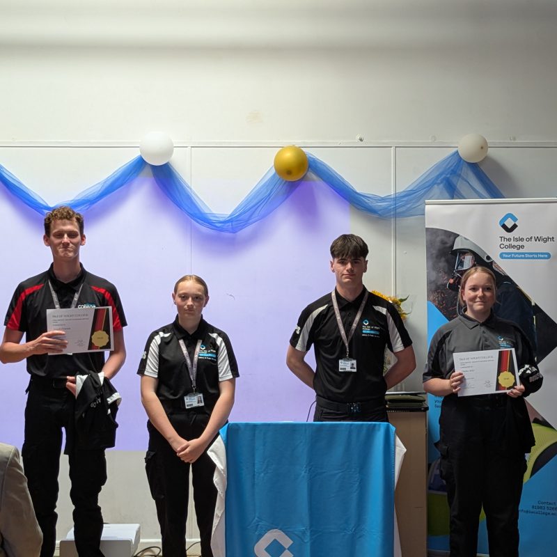 students stand at the front of the hall and pose with their certificates