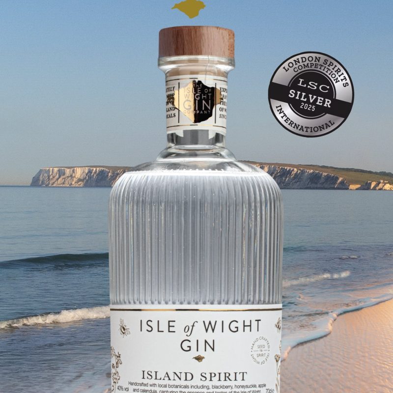 a advert depicting a gin bottle on a beach with the isle of wight gin logo at the top