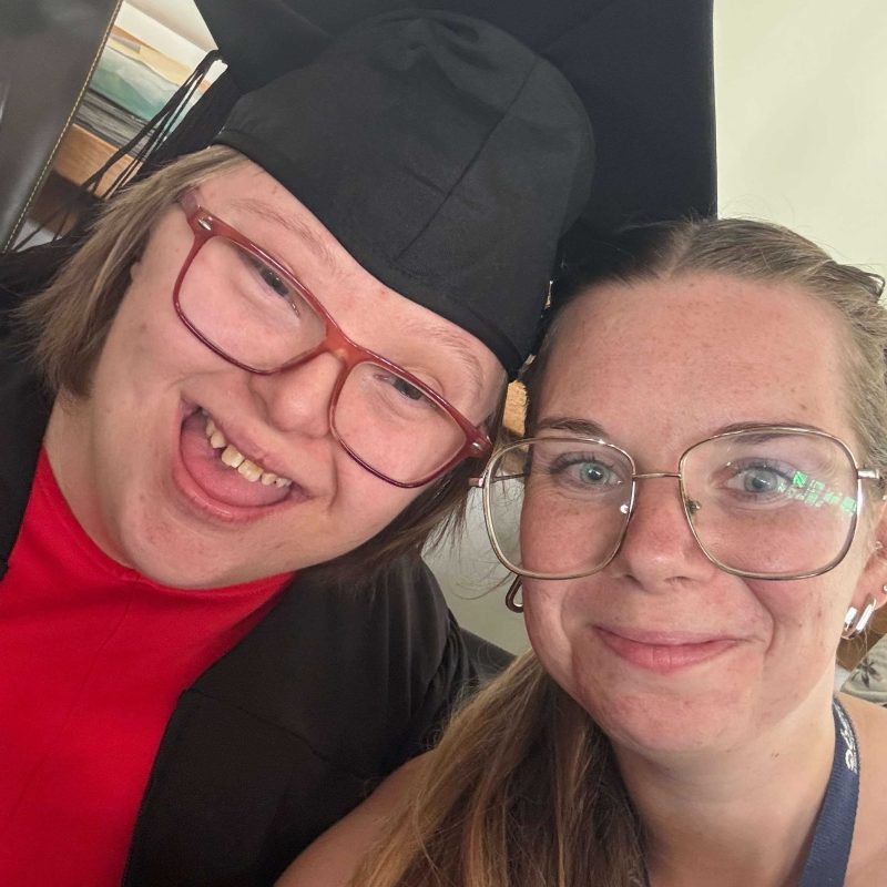 A Student wearing a graduation gown and a lecturer take a selfie