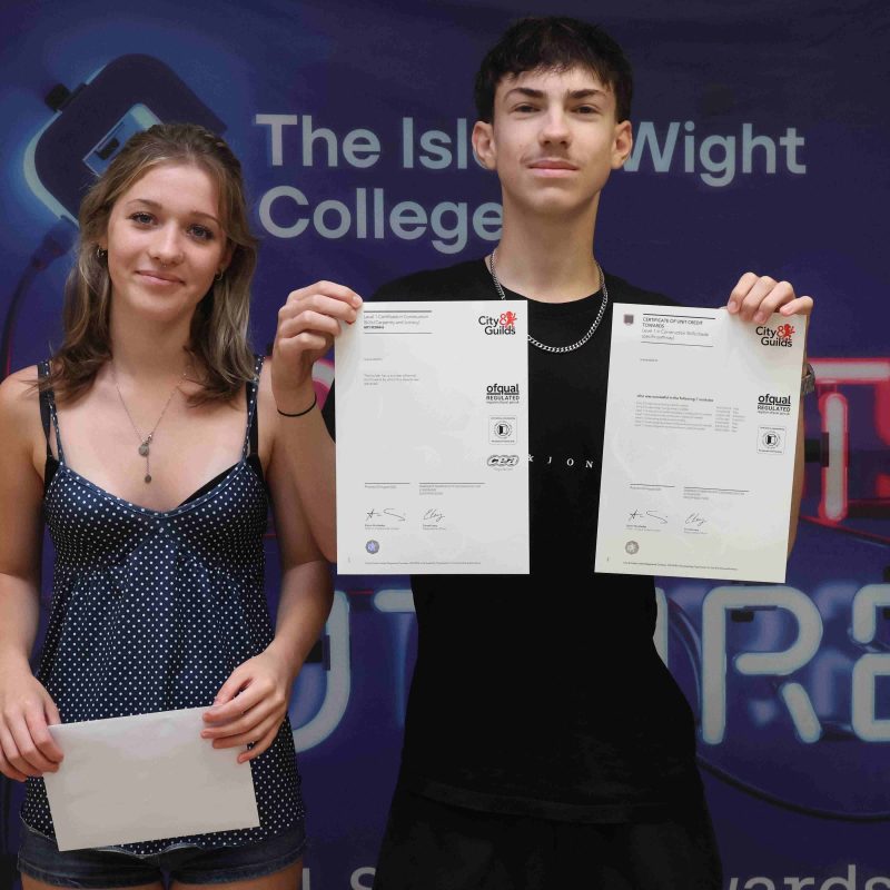 A male and a female student pose with their GCSE results