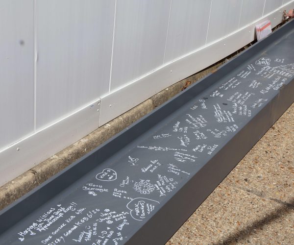 A picture of the beam on the ground filled with various different signatures and messages.