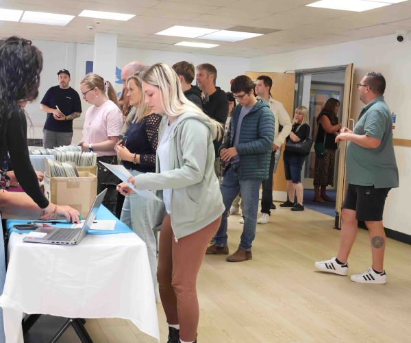 A Group of students queue at a desk to collect their results