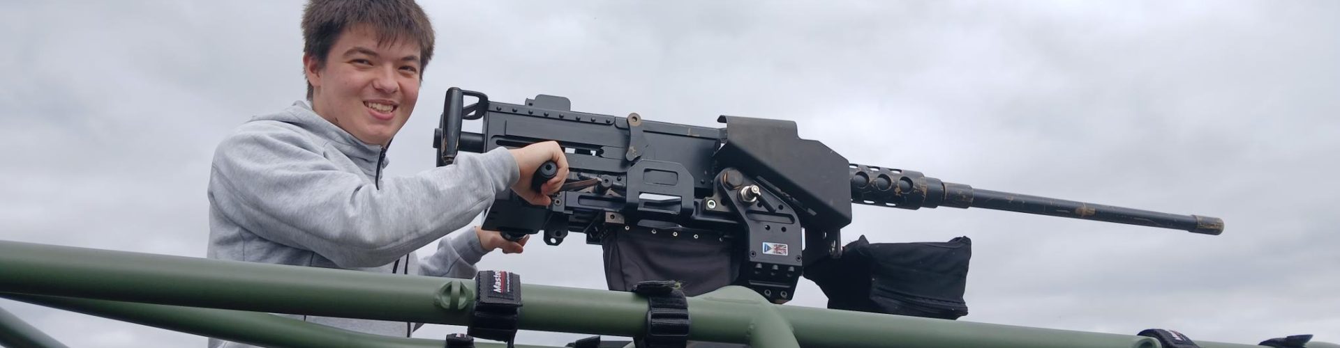 A Student poses with a mounted machine gun on a truck