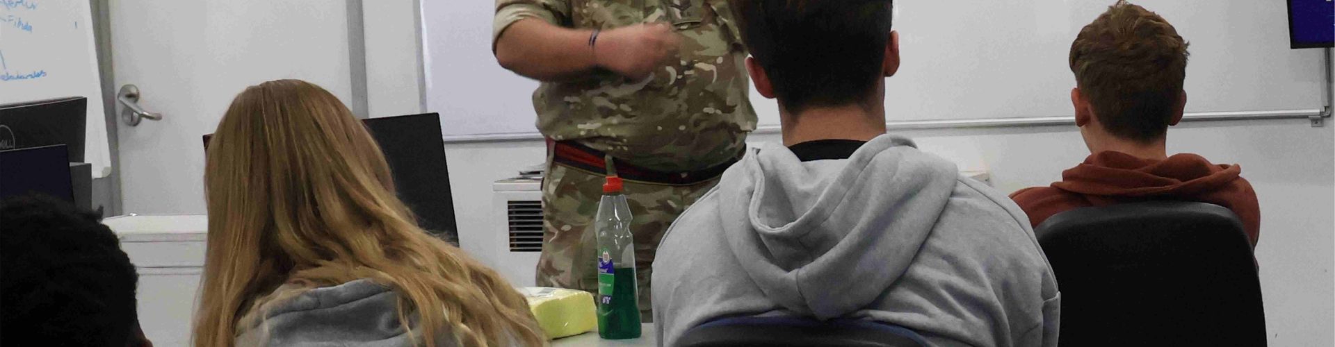 a man in a military uniform addresses students