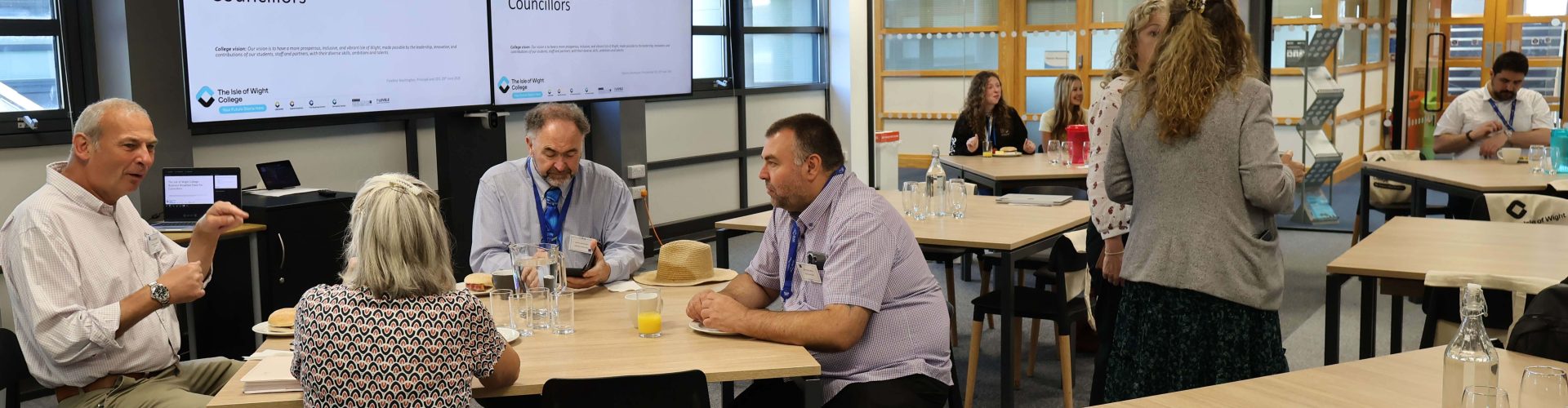 Councillors sit and enjoy their breakfast around tables.